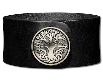 May include: Black leather bracelet featuring a silver-toned tree of life design. The bracelet has a buckle fastening.