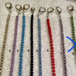 May include: Eight beaded chains with silver clasps, numbered 1 through 8. The chains are in the following colors: beige, lavender, turquoise, black, light blue, red, gray, and green.