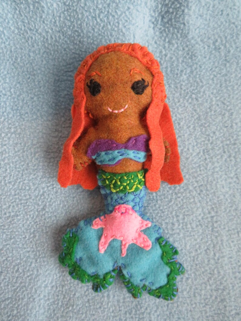 May include: A handmade felt mermaid doll with orange hair, a purple and blue top, and a green and blue tail with a pink starfish.