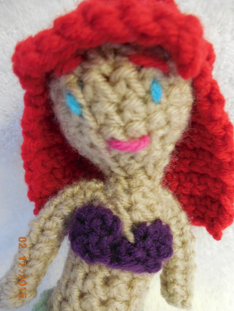 May include: Crocheted doll with red hair, a purple top, and blue eyes.