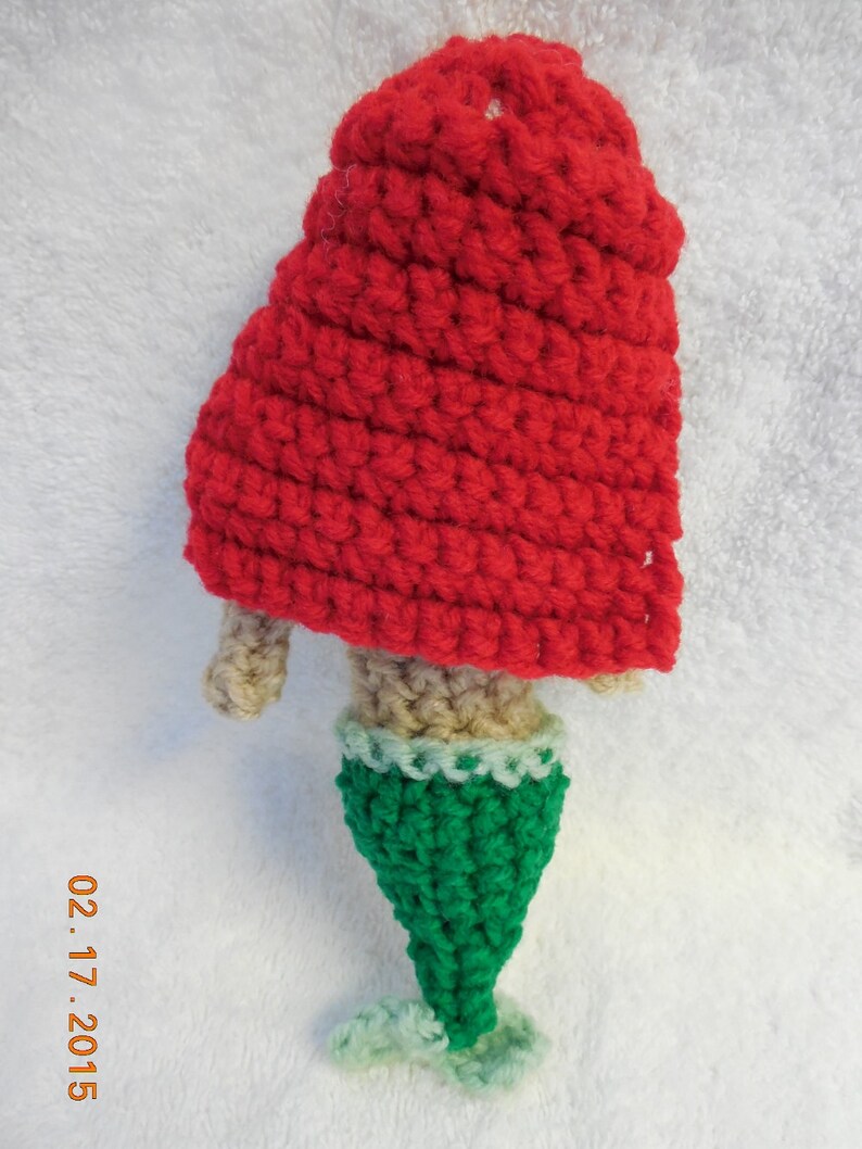 May include: A crocheted mermaid doll with a red hooded top and a green tail.