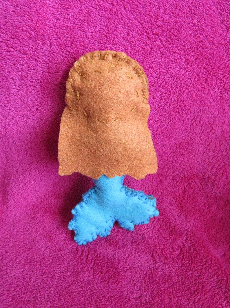 May include: A felt mermaid doll with a brown head and blue tail. The doll is handmade and has a simple design.