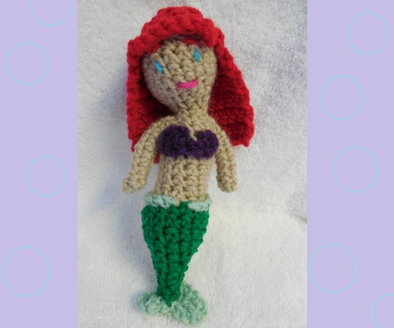 May include: Crocheted mermaid doll with red hair, a purple seashell bra, and a green tail.