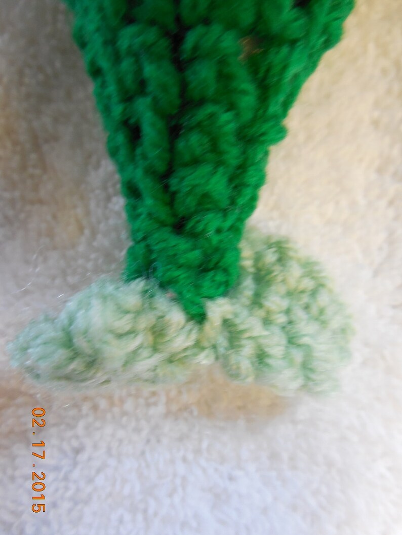May include: A green crocheted Christmas tree ornament with a white crocheted base.