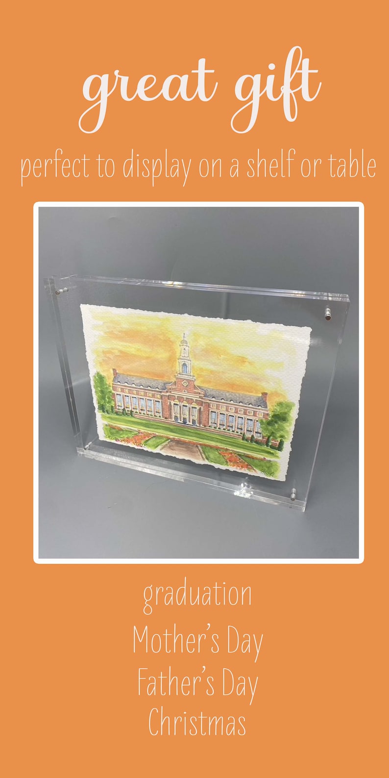 Pode incluir: Uma pintura em aquarela de um grande edif&iacute;cio de tijolos com uma torre central e um gramado verde, inserida em uma moldura de acr&iacute;lico transparente. A pintura apresenta tons quentes de c&eacute;u amarelo e laranja, &aacute;rvores verdes e um caminho.