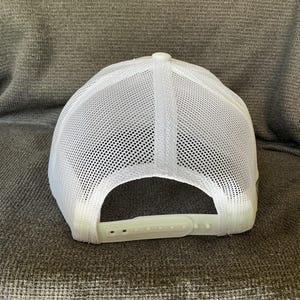 Peut inclure: Une casquette de type trucker blanche dot&eacute;e d'un panneau arri&egrave;re en maille respirante et d'un panneau avant blanc uni. La casquette comprend une fermeture r&eacute;glable en plastique &agrave; l'arri&egrave;re pour un ajustement personnalis&eacute;. Design blanc structur&eacute;.