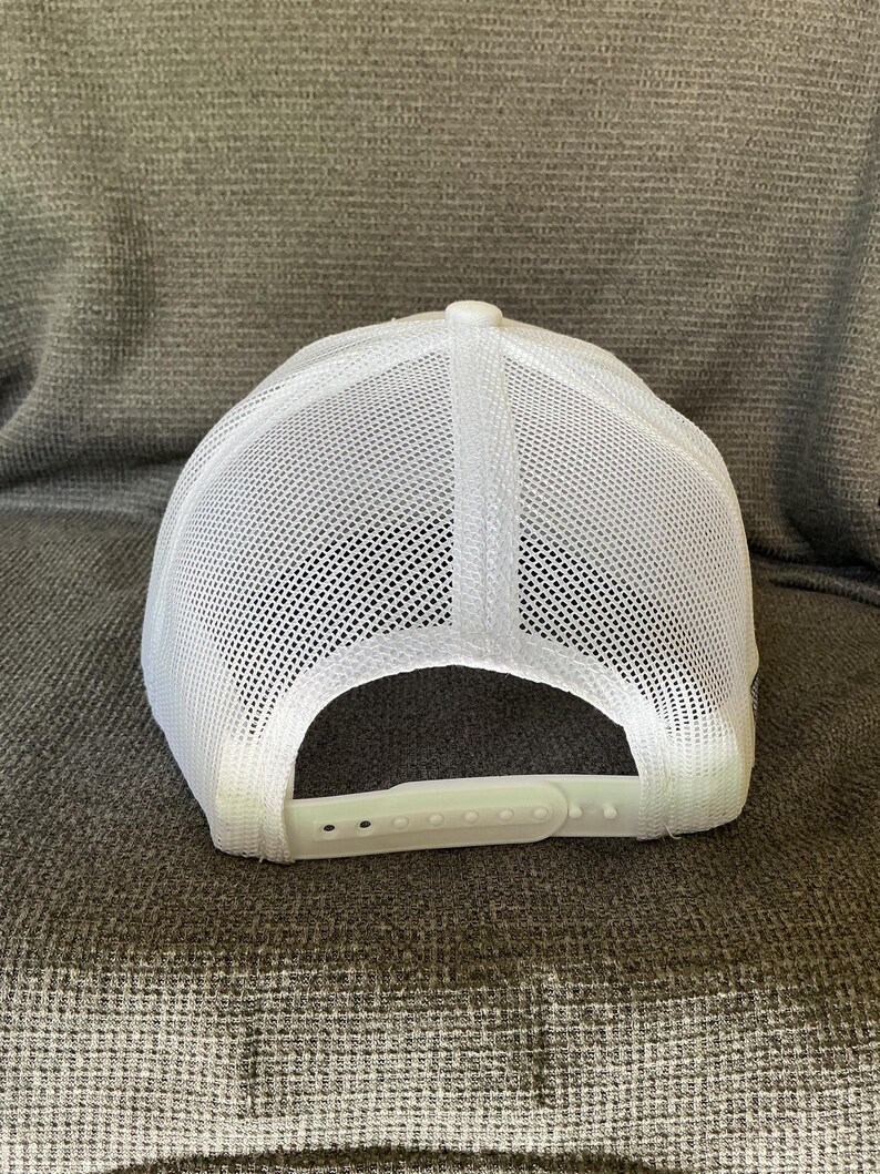 Peut inclure: Une casquette de type trucker blanche dot&eacute;e d'un panneau arri&egrave;re en maille respirante et d'un panneau avant blanc uni. La casquette comprend une fermeture r&eacute;glable en plastique &agrave; l'arri&egrave;re pour un ajustement personnalis&eacute;. Design blanc structur&eacute;.