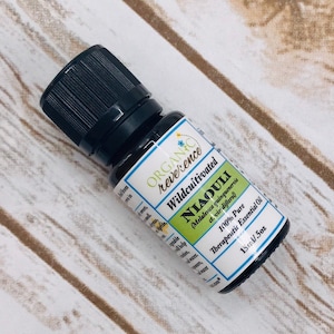 May include: A small, dark brown glass bottle with a black cap, labeled "ORGANIC reverence Wildcultivated NIAOULI (Melaleuca quinquenervia a. viridiflorol) 100% Pure Therapeutic Essential Oil 15ml/.5oz"