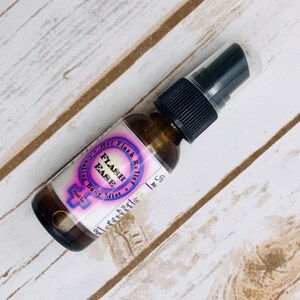Puede incluir: Una botella de vidrio marr&oacute;n con un pulverizador negro. La etiqueta es blanca con texto rosa y morado que dice "Flash Relief Hot Flash Cooling Body Mist" y un s&iacute;mbolo femenino rosa. La botella es de 30 ml/1 oz.