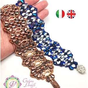 Op de afbeelding: Drie kralenarmbanden in een chevron-patroon. De armbanden zijn gemaakt van bruine, blauwe en witte kralen. De armbanden liggen op een hand, en de hand houdt de armbanden omhoog.