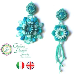 May include: A pair of turquoise and white beaded earrings with a flower design and a crystal accent. The earrings are handmade and feature a tassel.