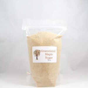 Pu&ograve; includere: Un sacchetto di plastica trasparente pieno di zucchero d'acero granulare. Il sacchetto ha un'etichetta che recita "Granulated Maple Sugar 8 oz."