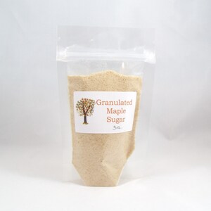 Pu&ograve; includere: Un sacchetto di plastica trasparente pieno di zucchero d'acero granulare. Il sacchetto ha un'etichetta che recita "Granulated Maple Sugar 3 oz."