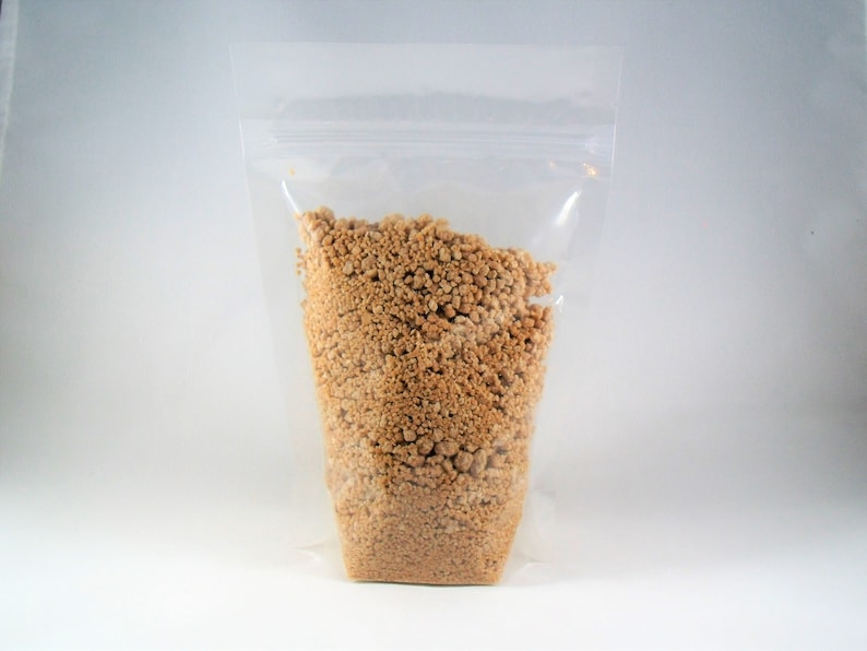 Pu&ograve; includere: Un sacchetto di plastica trasparente riempito con una sostanza friabile di colore marrone chiaro. Il sacchetto ha una chiusura a zip.