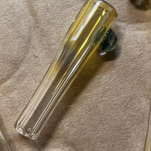 Può includere: Una pipa di vetro trasparente con un design a coste. La pipa è lunga circa 15 cm e ha un'estremità arrotondata.