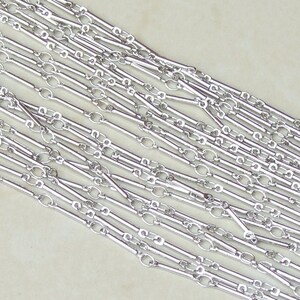 May include: Silver chain with alternating long and short links. The chain is made of metal and has a polished finish.