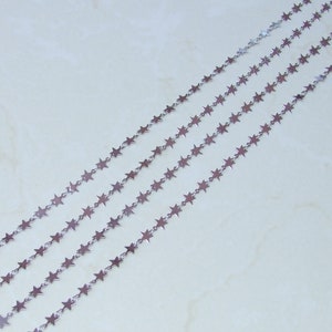 May include: Silver star chain, a delicate chain with small star-shaped links. The chain is shown in multiple strands, highlighting its versatility for jewellery making.