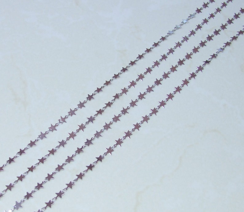 May include: Silver star chain, a delicate chain with small star-shaped links. The chain is shown in multiple strands, highlighting its versatility for jewellery making.
