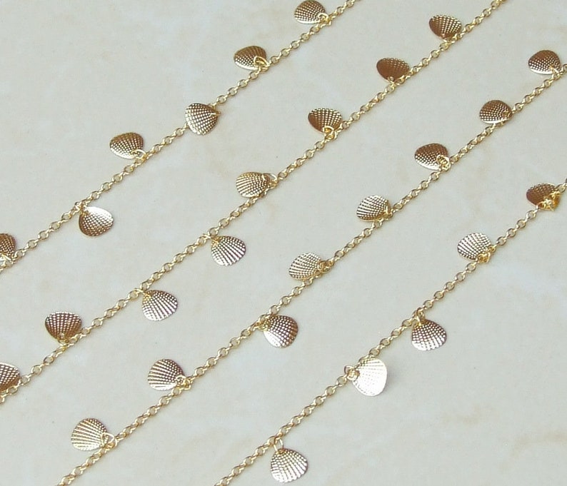 May include: Gold chain necklace with multiple rows of small, dangling, shell-shaped charms.
