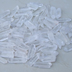 May include: A large pile of clear quartz crystal points. The points are various sizes and shapes, and they are all clustered together.