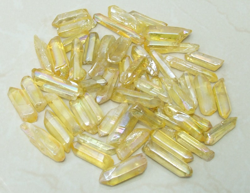 May include: A collection of iridescent yellow quartz points, also known as angel aura quartz, with a variety of sizes and shapes.