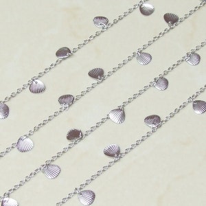 May include: A silver chain necklace with multiple strands featuring small, silver, shell-shaped charms.