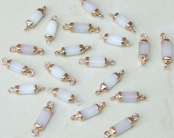 Peut inclure: Une collection de 18 perles de connexion rectangulaires blanches et dorées. Chaque perle a deux boucles dorées à chaque extrémité. Les perles mesurent environ 2,5 cm de long.