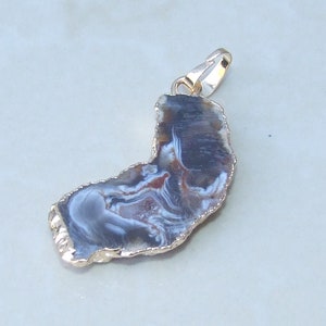May include: A gold-plated pendant featuring a natural agate slice with brown, white, and gray swirling patterns.