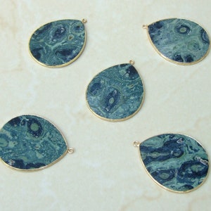 May include: Five teardrop-shaped green and blue gemstone pendants with gold-toned metal accents. The pendants have a marbled pattern.