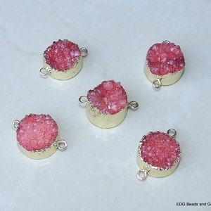 May include: Five round pink crystal gemstone connector charms with gold-toned metal accents. Each charm has two loops for attaching to jewelry.