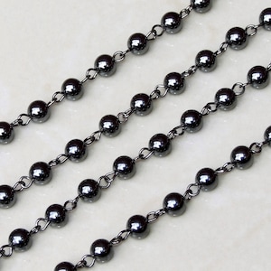 May include: A strand of black hematite beads with a silver chain. The beads are round and have a smooth, polished finish.