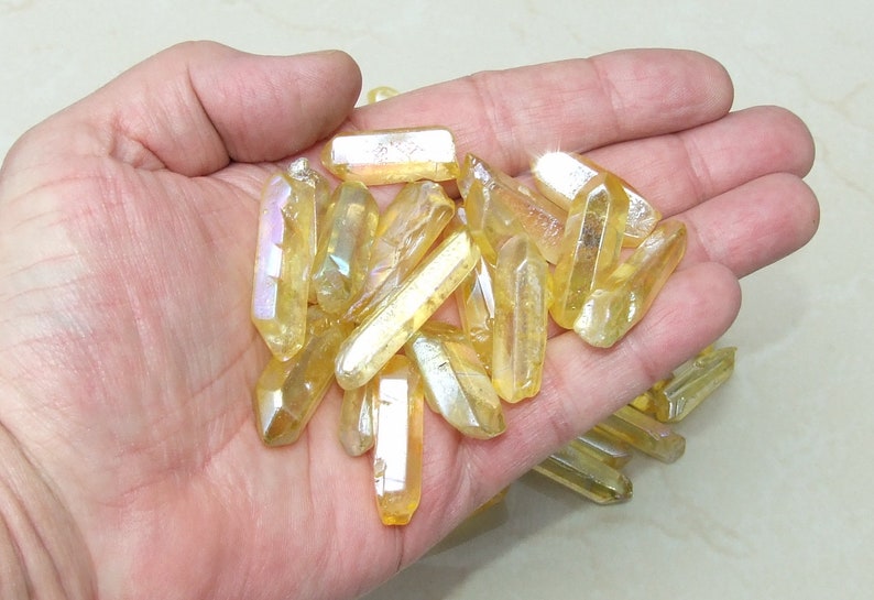 May include: A collection of iridescent yellow crystal points, also known as golden healer crystals, in various sizes and shapes.