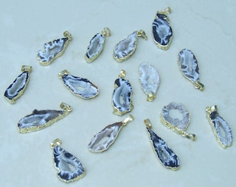 May include: A collection of 16 agate pendants with gold-plated edges. The agate is a light gray color with black veins and a hollow center. The pendants are all different shapes and sizes.