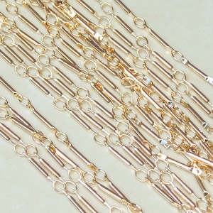 May include: Gold chain with alternating round and rectangular links. The chain is made of a thin, delicate metal and has a polished finish.