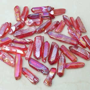 May include: A collection of approximately 30 red iridescent quartz points. The points are various sizes and shapes, with a natural, raw finish.