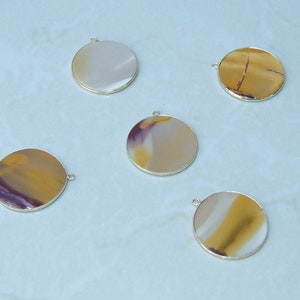 May include: Five round, silver-rimmed pendants with different patterns of brown, yellow, and purple agate.