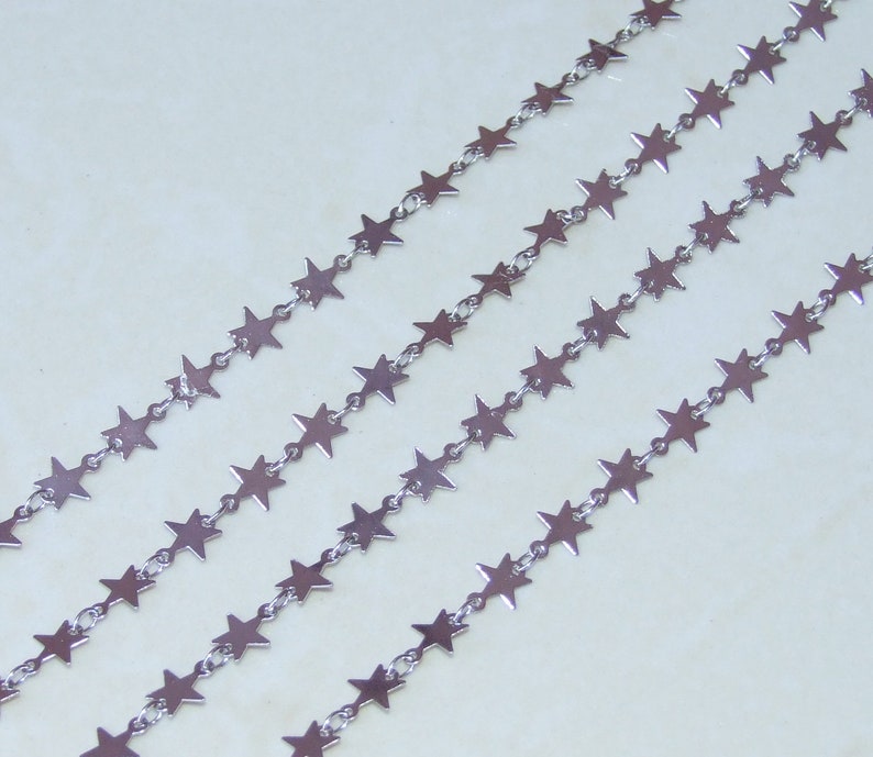 May include: Silver star chain with multiple strands of silver stars connected by small silver links.
