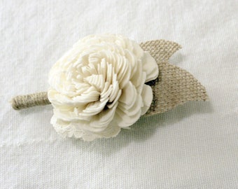 May include: A white sola flower boutonniere with a burlap bow. The flower is made of sola wood and is a popular choice for weddings and other special events.