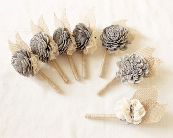 May include: Set of eight gray and beige flower boutonnieres with burlap and lace accents. The boutonnieres are tied with twine and have a rustic, farmhouse style.