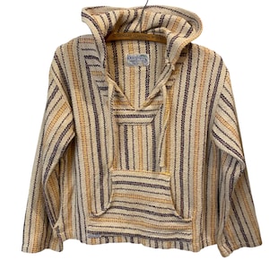 May include: A beige, brown, and yellow striped Baja hoodie with a hood and front pocket. The hoodie is made of a woven fabric and is hanging on a wooden hanger. The tag reads "G. Dengler Cleaning Works".