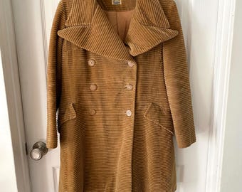 May include: A vintage, double-breasted corduroy coat in a warm, golden-brown hue. The coat features a wide collar, two rows of buttons, and two front pockets. The coat is hanging on a wooden hanger.