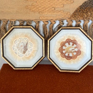 May include: Two octagonal framed pictures with gold trim, each containing a dried flower arrangement with a white background.