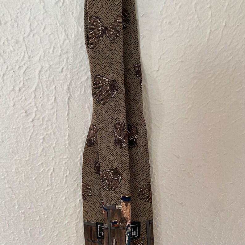 May include: A brown patterned tie with a brown and white chevron pattern. The tie features a repeated image of a baseball glove and a baseball player.