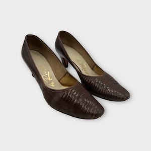 Peut inclure: Une paire d'escarpins en cuir marron avec un motif texturé. Les chaussures ont un bout pointu et un petit talon. L'intérieur de la chaussure porte le texte doré "de Rouge".