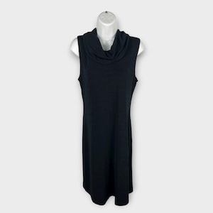 May include: A sleeveless black dress with a cowl neck, displayed on a white mannequin. The dress has a simple, elegant design, suitable for various occasions. The fabric appears to be a soft, solid material.