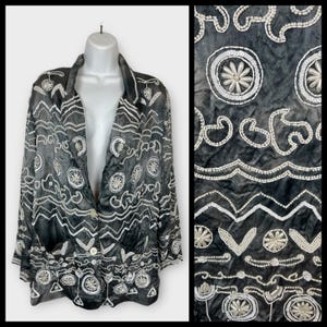 May include: Black blazer with white beaded embellishments. The jacket features a notched collar, two front pockets, and a single-button closure. The design includes floral and geometric patterns.