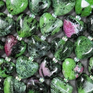 May include: A collection of green, black, and pink heart-shaped stones. The stones are arranged in a close-up view, showing their intricate patterns and textures.