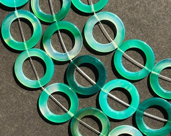 May include: A strand of green agate donut beads. The beads are a light green colour with a white centre and a smooth, polished finish.