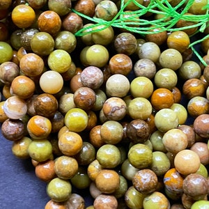 May include: A strand of green, brown, and yellow gemstone beads. The beads are round and have a smooth, polished finish.
