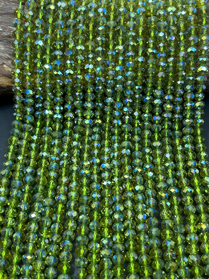 May include: A strand of green faceted glass beads. The beads are small and round, with a slight iridescent sheen.